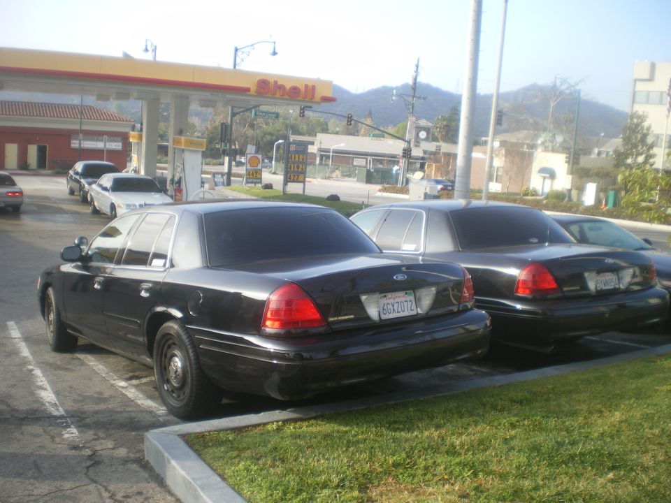 Black 2004 Ford Crown Victoria parked at a Shell gas station, with another similar car behind it