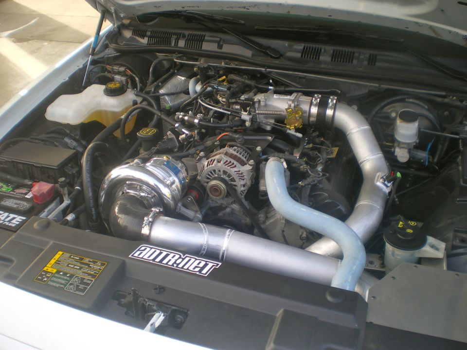 Engine bay with a large turbocharger and custom piping. Sticker says "BDTR:net"