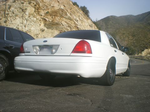 2004 Ford Crown Victoria - Rear view of a white Ford Crown Victoria parked on a mountain road beside another vehicle.