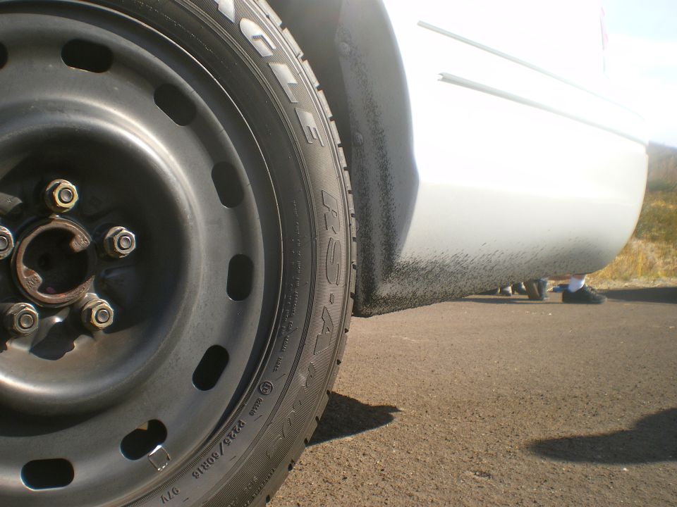 Close-up of a steel wheel and white side panel of a car