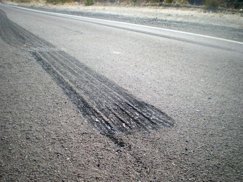 2004 Ford Crown Victoria - Evidence of tire marks on the asphalt surface of a road, indicating recent vehicle activity.