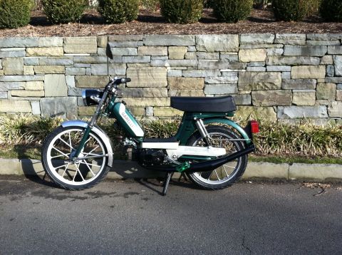 1981 Garelli Rally Sport - A green moped is parked on the side of a road in front of a stone wall.