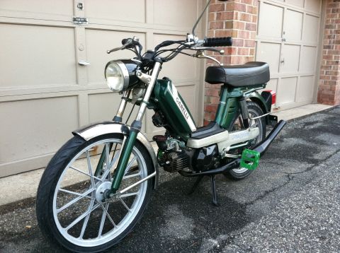 1981 Garelli Rally Sport - Green moped with chrome fenders and 'GARELLI' text on the side, parked in front of a garage.