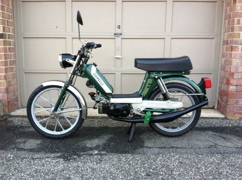 1981 Garelli Rally Sport - A green moped with chrome fenders and a black seat is parked in front of a closed garage door.