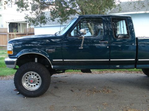 1994 Ford F-250 - This 1994 Ford F-250 pickup truck is shown from the side, its dark green paint and chrome accents.