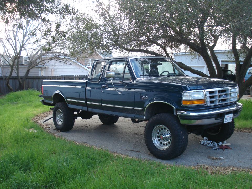 Dark blue 1994 Ford F-250 pickup truck with lifted suspension, parked on a driveway