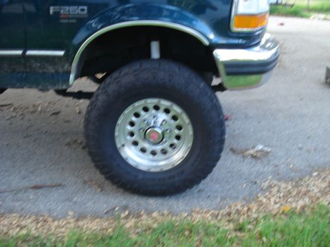 1994 Ford F-250 - The front wheel and fender of a dark green Ford F-250 truck are shown in this close-up photo.