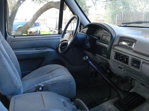 1994 Ford F-250 - The interior of a 1994 Ford F-250 truck, the dashboard, steering wheel, and seats, with another vehicle visible through the window.