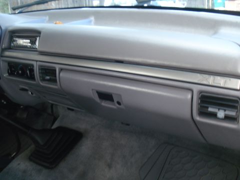 1994 Ford F-250 - The interior of a truck shows the dashboard area with the glove compartment, radio, and air vents. XLT trim is visible.
