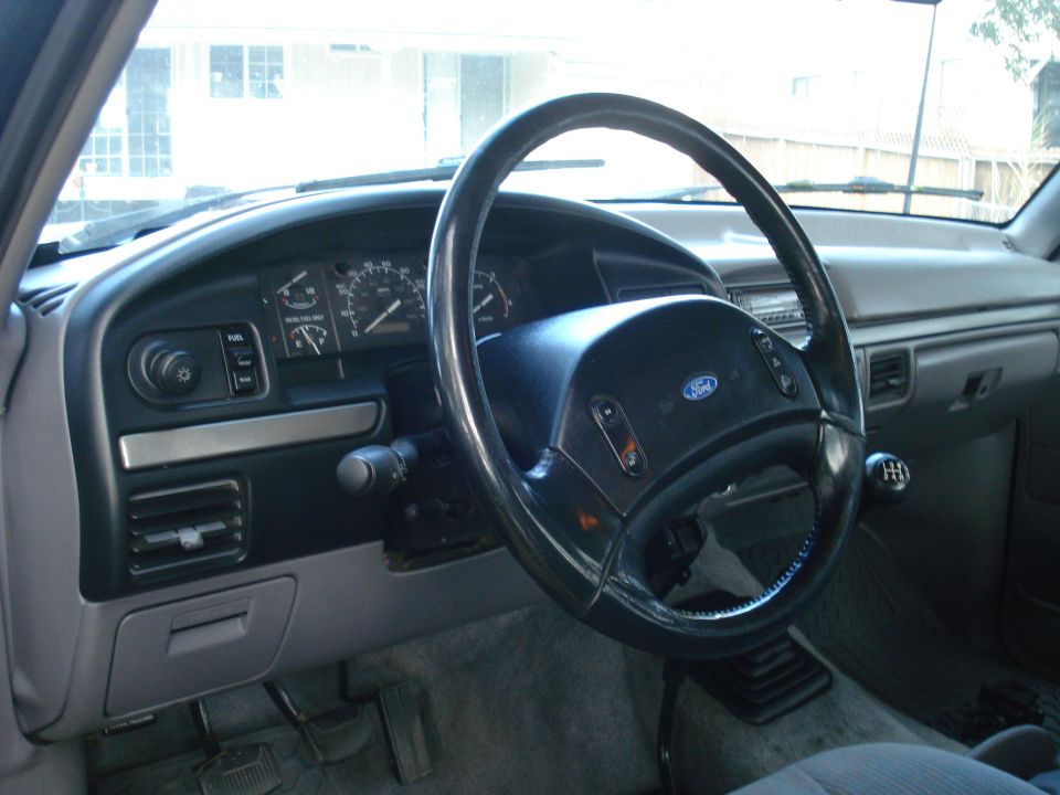 Gray dashboard and steering wheel of a Ford truck, showing the instrument cluster and gear shift