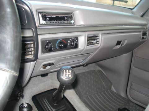 1994 Ford F-250 - The interior of a truck shows a manual transmission shifter, climate controls, and an aftermarket Kenwood stereo.