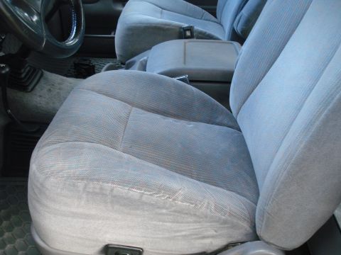 1994 Ford F-250 - The interior of a truck shows worn fabric seats and a center console with a gear shifter.