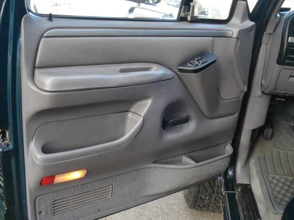 Green truck's gray interior door panel with power window controls and a red and amber reflector light
