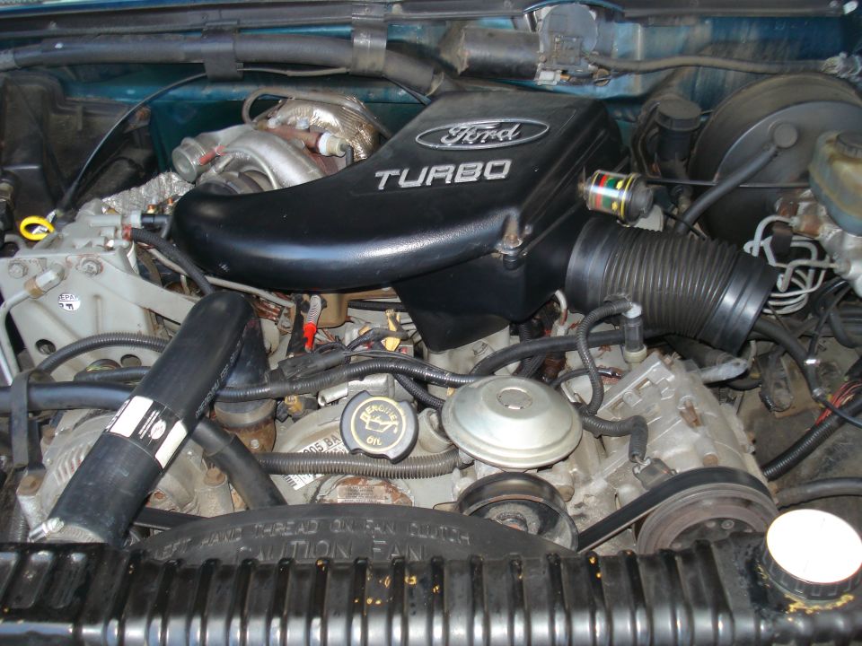 Ford 7.3L IDI Turbo diesel engine bay with "Ford TURBO" air intake cover. Oil cap visible