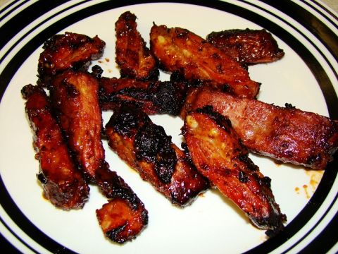 1989 Ford Bronco - A close-up view of several glazed ribs on a white plate with black and white striped rim.