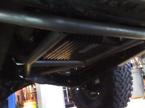1996 Ford Bronco - The underside of a heavily modified vehicle reveals custom suspension and roll cage work, with a large off-road tire visible.