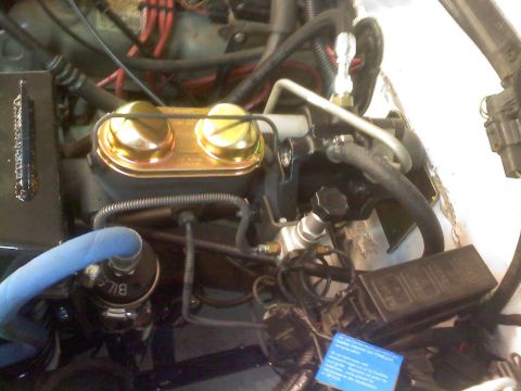 1996 Ford Bronco - Close-up view of engine bay components, including a gold brake fluid reservoir and various hoses.