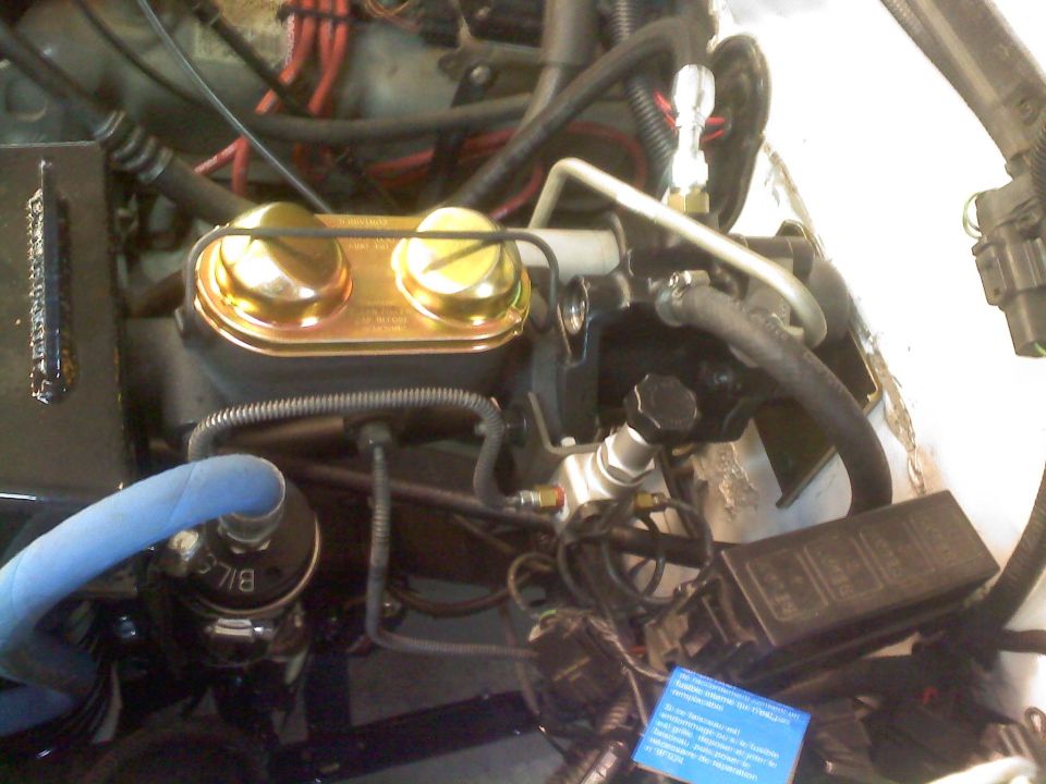 Engine bay with gold brake fluid reservoir, blue hose, and black fuse box