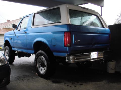 1995 Ford Bronco - Rear view of a blue and white 1995 Ford Bronco, showing its distinctive body style and rear bumper.