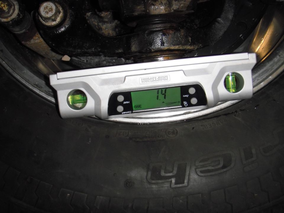 Digital level showing 1.4 on a tire next to suspension components