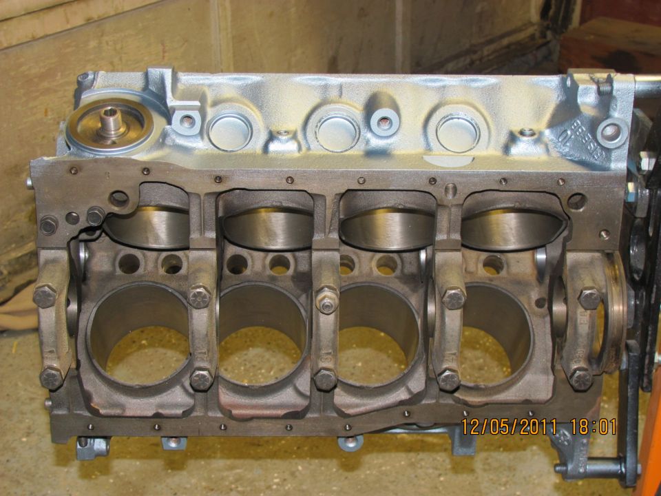 Engine block with four pistons visible, mounted on an engine stand. Date stamp 12/05/2011