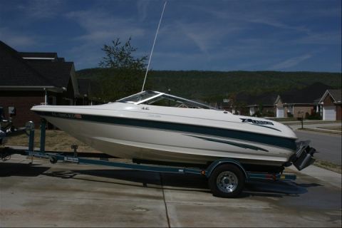 1978 Chevrolet Camaro - A white boat with a teal stripe is parked on a trailer in a driveway, with houses visible behind it.