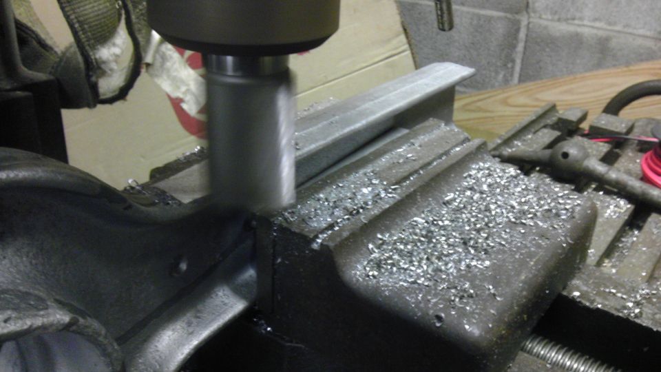 Milling machine cutting metal workpiece held in a vise, with metal shavings scattered