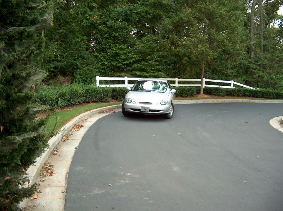 Silver coupe parked on a paved driveway, front view