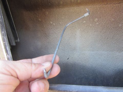 1964 Ford Ranchero - A person is holding a metal rod, likely a door lock actuator rod, inside a car's door panel.