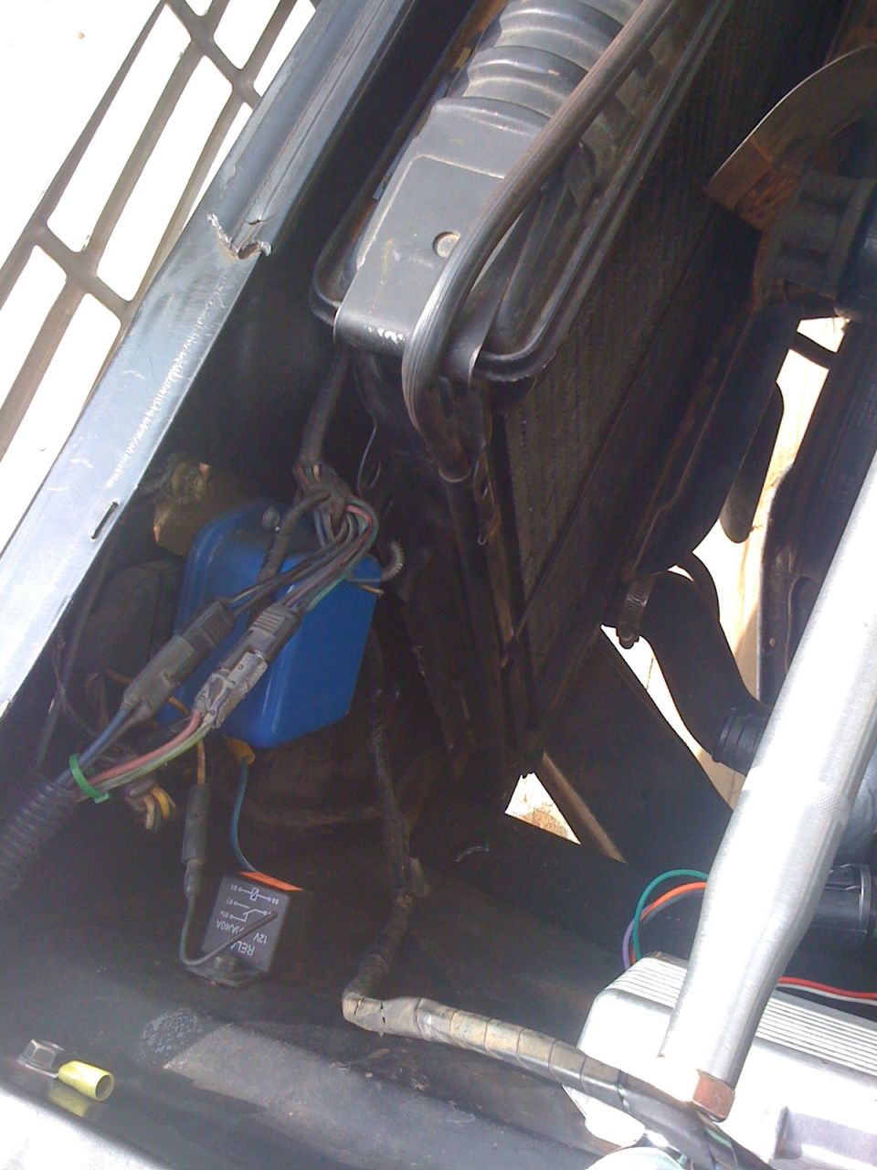 Engine bay with radiator, blue electrical component, and wiring