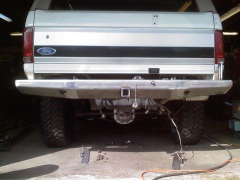1996 Ford Bronco - Rear view of a silver 1987 Ford Bronco with a custom bumper and visible drivetrain components.