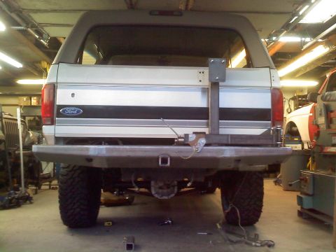 1996 Ford Bronco - The rear of a Ford Bronco is shown with a custom bumper and hitch, with another vehicle in the background.