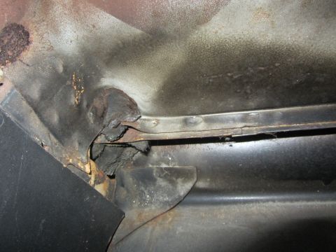 1964 Ford Ranchero - Close-up view of heavily rusted interior metal paneling with a black trim piece visible.
