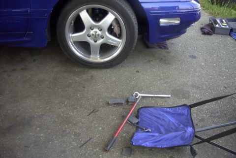 1997 Ford Taurus - Tools are laid out on the asphalt next to a blue car, suggesting maintenance is underway.
