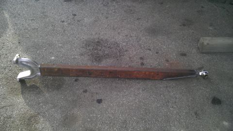 1987 Ford Ranger - A single suspension control arm is shown lying on asphalt pavement.