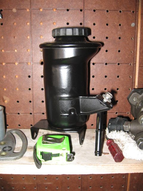 1993 Toyota 4Runner - A black power steering fluid reservoir is shown with a tape measure and other automotive parts on a shelf.
