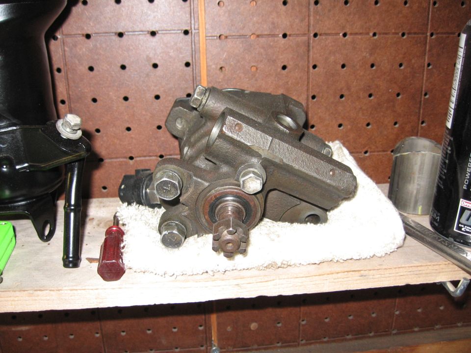 Power steering pump on a shelf with a screwdriver and other parts