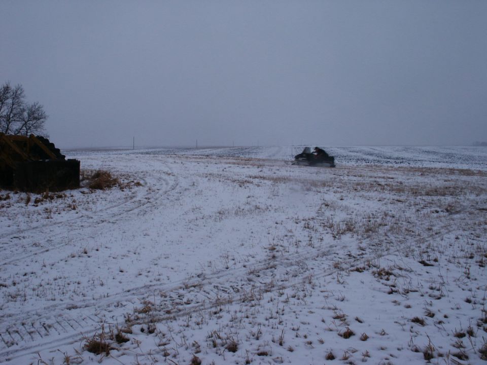 Snowmobile in a snowy field near a stone structure