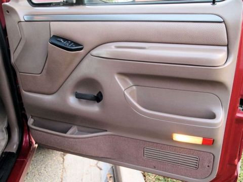 1994 Ford Bronco - The interior door panel of a 1994 Ford Bronco shows the armrest, door handle, and power window controls.