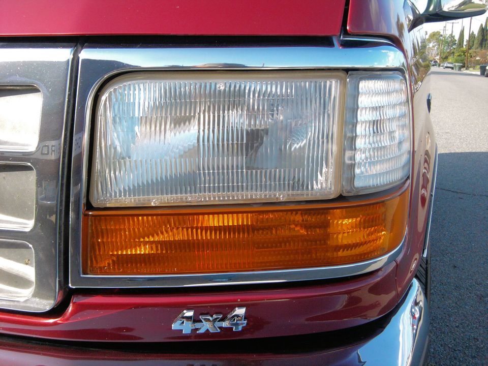 Red Ford truck front corner with chrome grille and amber turn signal. 4x4 badge visible
