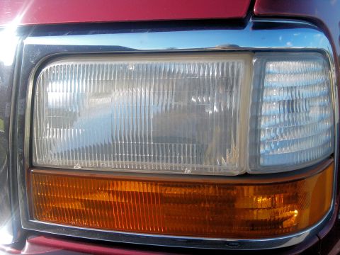 1994 Ford Bronco - Close-up of the headlight and amber turn signal on a red 1994 Ford Bronco.