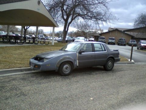 1987 Ford Bronco - This sedan appears to be undergoing repairs or modifications, with mismatched body panels visible.