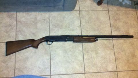 2010 Champion 188 - A shotgun with a wooden stock and barrel is displayed on a tiled floor.