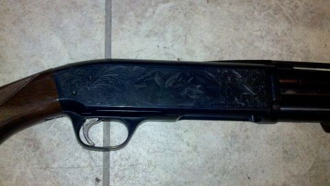 2010 Champion 188 - This shotgun features intricate engraving on its receiver and a wooden stock, photographed against a tiled surface.