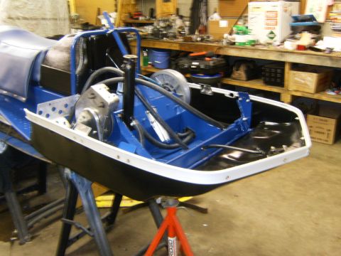 2000 Ford E350 - A snowmobile chassis, painted blue and black, is supported by red and black stands in a workshop.