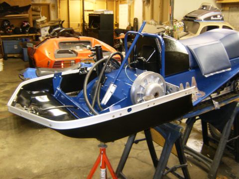 2000 Ford E350 - Snowmobile chassis undergoing work in a garage with other vehicles present.