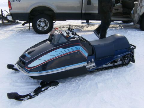 2000 Ford E350 - A snowmobile sits in the snow next to a pickup truck with its door open.