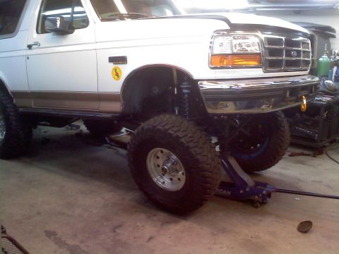 1996 Ford Bronco - A white 1996 Ford Bronco is shown with its suspension lifted and large off-road tires mounted.