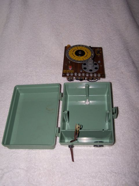 1973 Ford Bronco - A disassembled wiring harness component with a timer dial sits next to its green plastic enclosure.