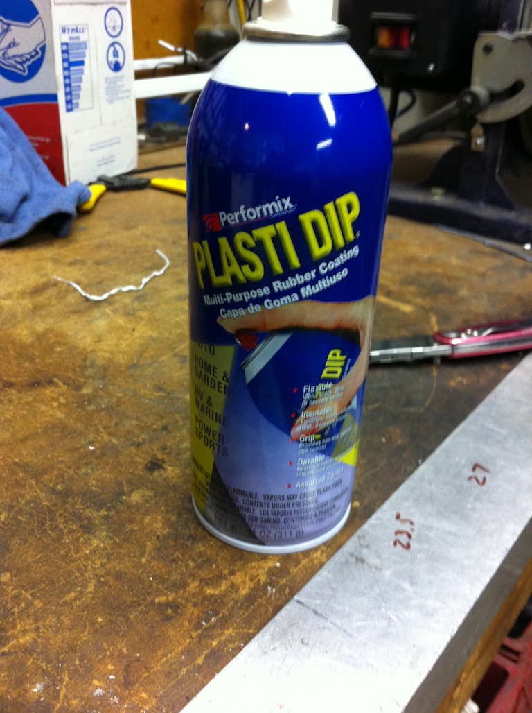 Performix Plasti Dip spray can on a workbench beside a marked aluminum bar